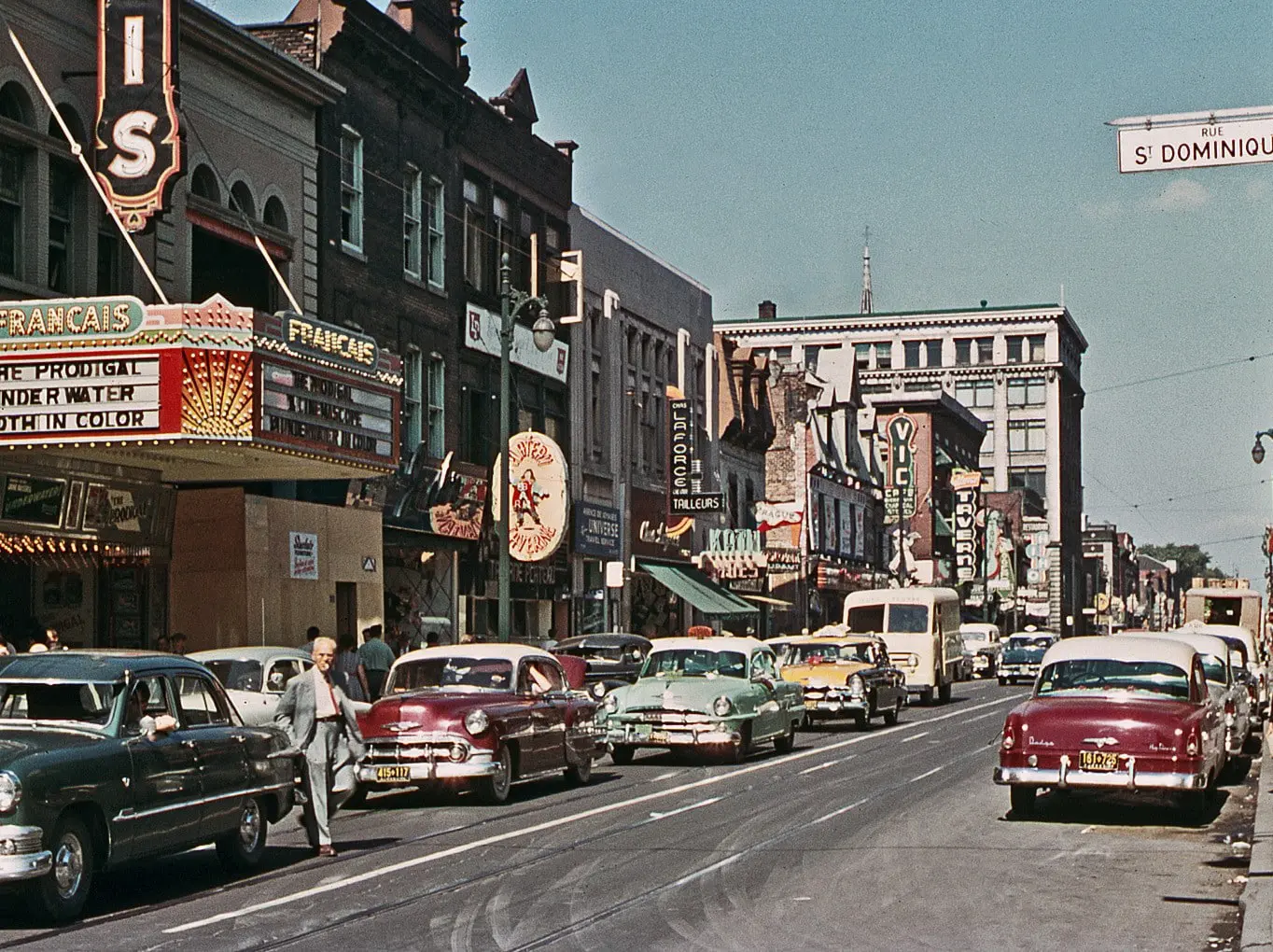 Vue historique de Montréal montrant le Théâtre Français, les commerces et les automobiles de la rue Sainte-Catherine Est.